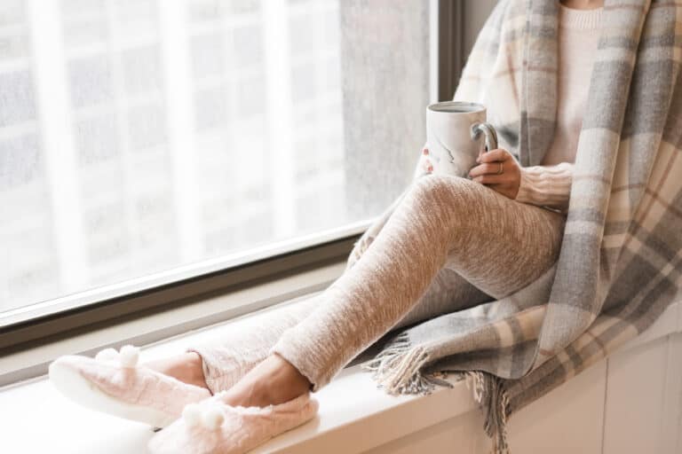 advice for speaking to the bereaved. picture of woman dressed in cozy clothes staring out the window.